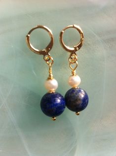 Earrings with fine Lapis-Lazuli stones surrounded by gold-plated cups and topped with a freshwater pearl. Two quality, deep blue Lapis Lazuli beads measuring 9mm in diameter. Two white freshwater pearls measuring 5 mm and cups of gold plated pearls of 4 mm. The earrings are 4cm or an inch and a half. Pretty plated hoops nicely embellish these earrings with a minimal style but of quality. You will find an extensive literature on stones and crystals on the web which you can consult at will. Lapis Beaded Jewelry Earrings, Lapis Lazuli Beads, Blue Lapis Lazuli, Lapis Lazuli Stone, Blue Lapis, White Freshwater Pearl, Minimal Style, Minimal Fashion, Deep Blue