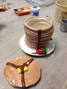 there is a cake made to look like a stack of pancakes on a plate with chocolate icing