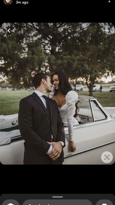 a man and woman standing next to each other in front of a white convertible car