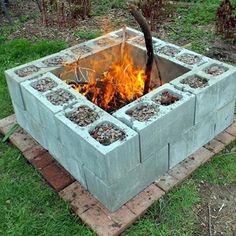 an outdoor fire pit made out of cinder blocks with flames coming out of the top