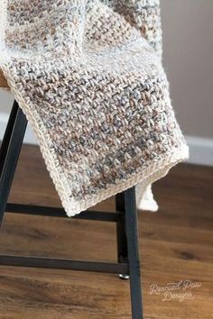 a close up of a crocheted blanket on a chair with a black frame