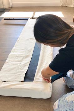 a woman laying on the floor with her feet up and making a piece of fabric