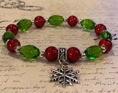 Beautiful green glass barrel beads and vibrant red Wonder beads are paired with a silver or gold plated snowflake charm to create an easy to wear stretch bracelet that's perfect for the holidays or anytime you're feeling festive. The bracelet is strung on 1mm Stretch Magic cord and easily rolls over your hand to rest on the wrist. The 7.0 inch bracelet is featured in the photograph of my hand but I can custom make any size you need. Just select the size you need or convo me with your request. Pl Snowflake Bracelet, Winter Jewelry, Bracelets Diy, Christmas Bracelet, Beaded Bracelet Patterns, Beaded Bracelets Diy, Jar Crafts, Diy Earrings, Bead Crafts