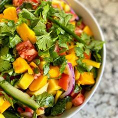 a white bowl filled with lots of veggies and salad dressing on top of a table