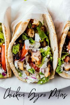 three chicken burritos with lettuce, tomatoes and other toppings on a white plate