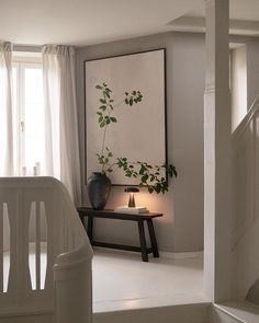 a living room with white furniture and a painting on the wall next to a stair case