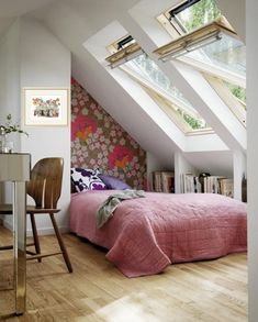 an attic bedroom with slanted ceilings and pink bedding, wooden flooring and white walls