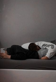 a young man laying on top of a bed next to a lamp and remote control