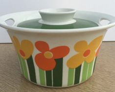 a ceramic container with flowers painted on the front and sides, sitting on a table