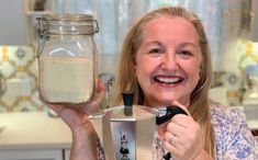 a woman holding up a jar and blender