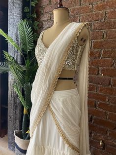 Ivory georgette pre-stitched ruffle saree with golden detailing, paired with Ivory raw silk blouse in signature Mirror and Pearl hand embroidered blouse Elegant White Designer Pre-draped Saree, Elegant Pre-draped Saree With Gota Work, Festive Cream Georgette Pre-draped Saree, Elegant Fitted Pre-draped Saree With Gota Work, Elegant Georgette Blouse With Gota Work, Georgette Pre-draped Saree With Gota Work For Reception, Elegant Georgette Choli With Gota Work, Elegant White Chinon Pre-draped Saree, Elegant White Pre-draped Chinon Saree