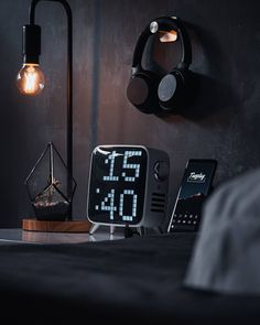 an alarm clock sitting on top of a table next to a phone and headphones