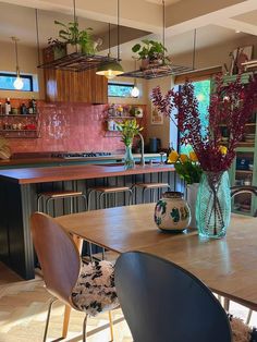 a table with chairs and vases filled with flowers on top of it in a kitchen