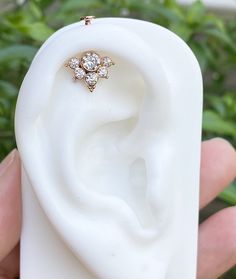 a close up of a person holding a fake ear with a diamond ring on it