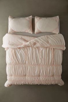 a bed with two pillows on top of it next to a pillow case and blanket