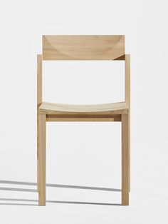 a wooden chair sitting on top of a white floor next to a shadowless wall