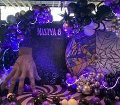 an assortment of balloons and decorations on display in a room with purple lights, black and white