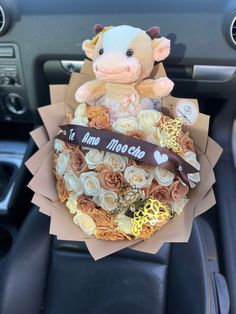 a stuffed cow sitting in the center of a car decorated with flowers and ribbon that says it's my month