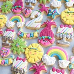 some cookies are decorated with different designs and colors, including rainbows, sunflowers, clouds, and flowers