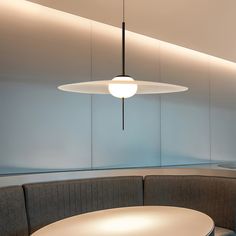 a round table with two chairs and a light hanging from it's ceiling in an office setting