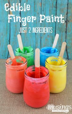 four jars filled with edible finger paint and popsicle sticks in them, sitting on a table