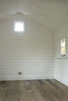 an empty room with wood floors and white walls