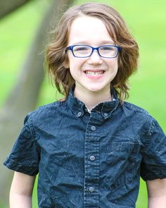 a young boy wearing glasses smiling for the camera