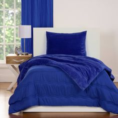 a blue comforter set on a white bed