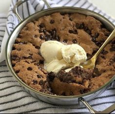 a cookie and ice cream dish in a pan on a towel with a spoon next to it