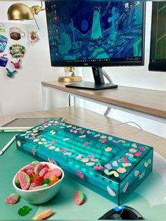 a desk with a computer monitor, keyboard and bowl of candy