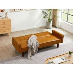 a brown leather bench sitting on top of a hard wood floor next to a window