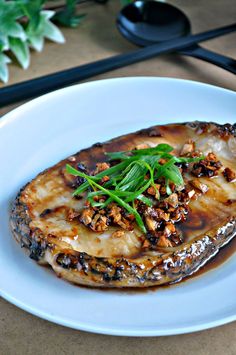 a white plate topped with an eggplant covered in sauce and garnish