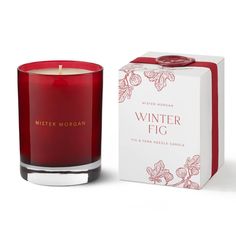 a red candle sitting in front of a white box with the words winter fig on it