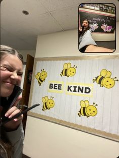 a woman taking a selfie in front of a bee kind sign