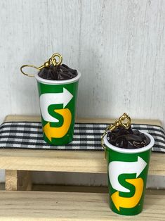 two green and white buckets sitting on top of a wooden bench next to each other