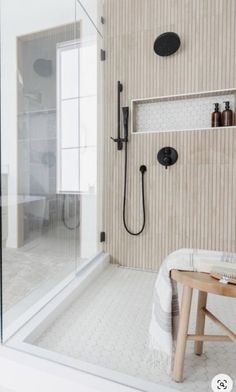 a bathroom with a walk in shower next to a wooden bench