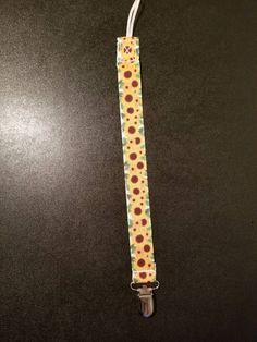 an orange and yellow polka dot lanyard on a black table with a metal hook