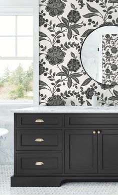 a black and white bathroom with floral wallpaper on the walls, sink and mirror