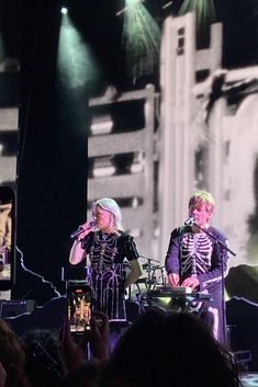 two men in skeleton costumes on stage with microphones