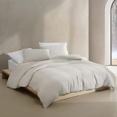 a bed with white sheets and pillows in a room