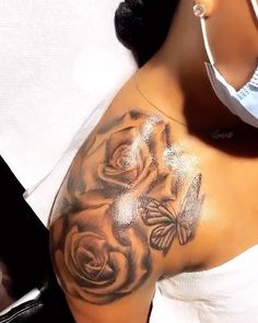 a close up of a woman's shoulder with flowers and butterflies on her arm