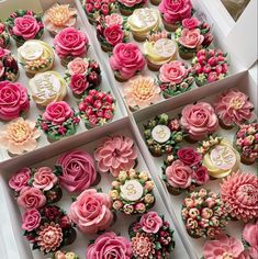 four boxes filled with cupcakes covered in pink and white frosting flowers on top of each one