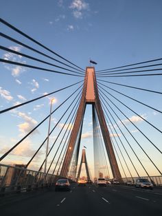 cars driving on a bridge with tall buildings in the back ground and blue sky above