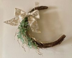 a wreath hanging on the wall with a bow and greenery attached to it's side