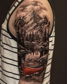 a man's arm with a mountain scene on it and a red canoe in the water