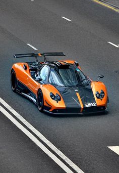 an orange and black sports car driving down the road