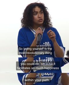 a woman holding a microphone in front of her face with the words, so loving yourself is the most revolutionary thing you could do