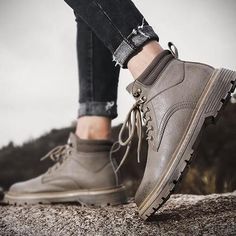 a person standing on top of a rock with their feet in the air and wearing grey shoes