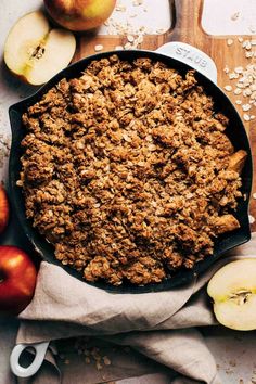 an apple crisp in a cast iron skillet next to sliced apples