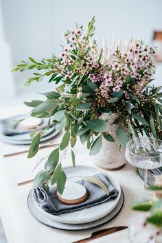 a white table topped with plates and vases filled with flowers